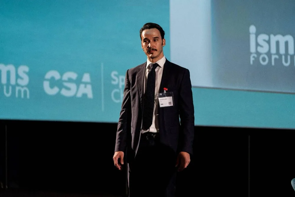 Antonio con micrófono sobre el escenario, ante una proyección de ISMS Forum